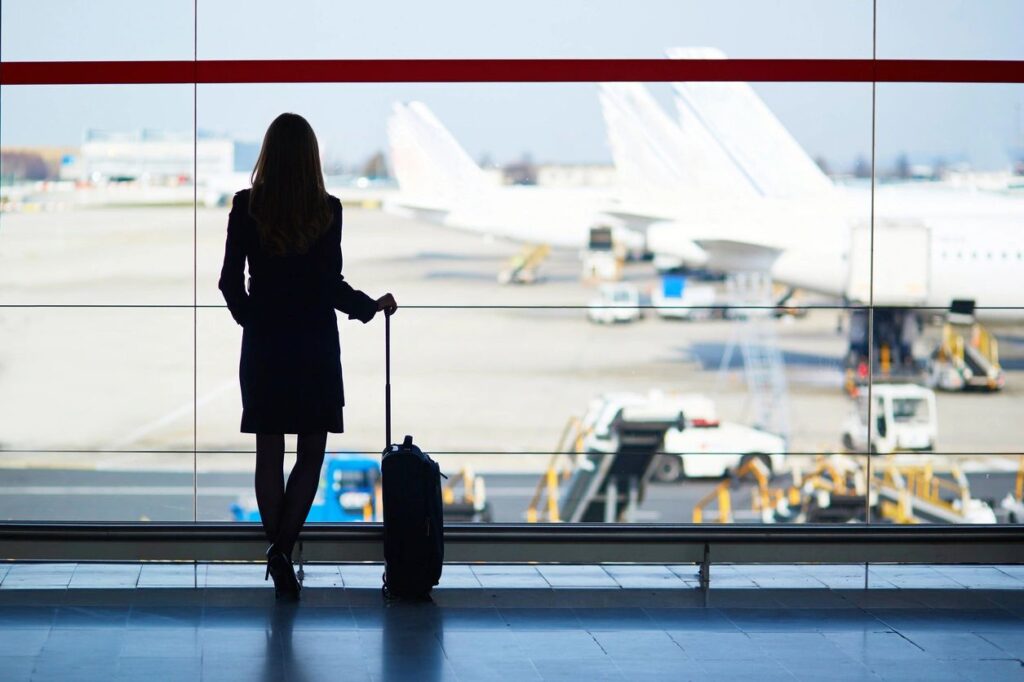 woman with suitcase looking at plane